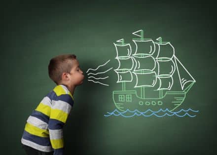 Child blowing a chalk sailboat